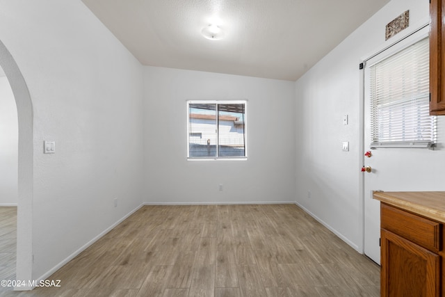 spare room featuring light hardwood / wood-style floors and vaulted ceiling