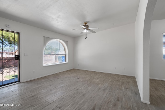 unfurnished room with ceiling fan, light wood-type flooring, and a wealth of natural light