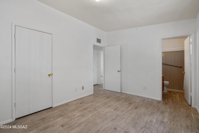 unfurnished bedroom with connected bathroom, a closet, and light wood-type flooring