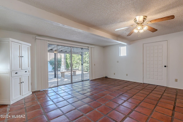 tiled spare room featuring beamed ceiling, ceiling fan, and a textured ceiling