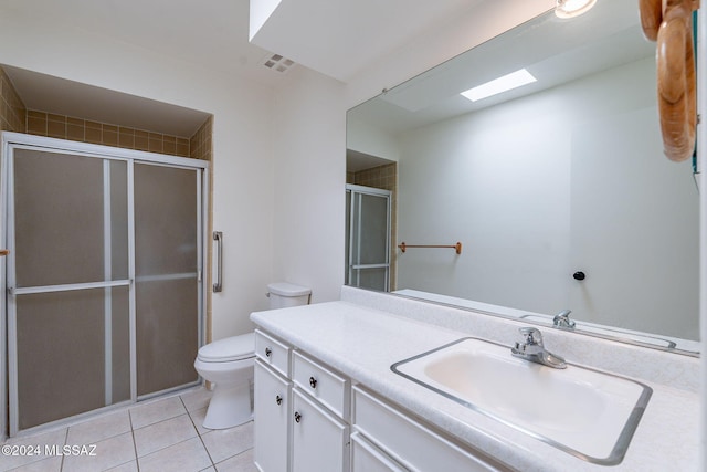 bathroom featuring tile patterned flooring, vanity, a shower with shower door, and toilet