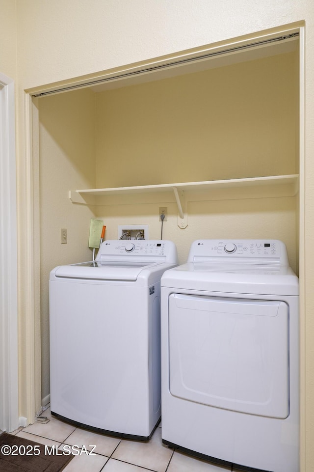 washroom with washer and clothes dryer and light tile patterned floors