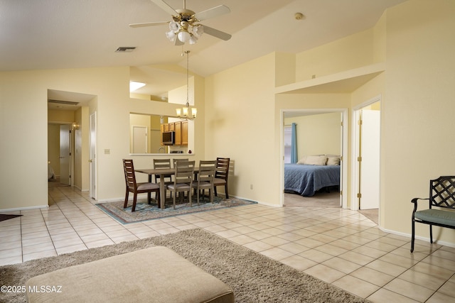 dining room featuring ceiling fan with notable chandelier, light tile patterned flooring, and lofted ceiling