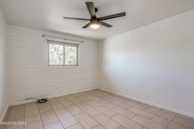 unfurnished room featuring ceiling fan and brick wall