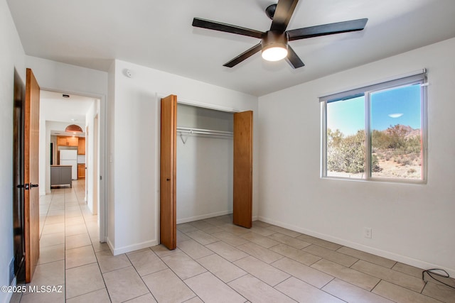 unfurnished bedroom featuring ceiling fan, white refrigerator, light tile patterned floors, and a closet