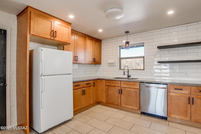 kitchen featuring backsplash, stainless steel dishwasher, sink, pendant lighting, and white refrigerator