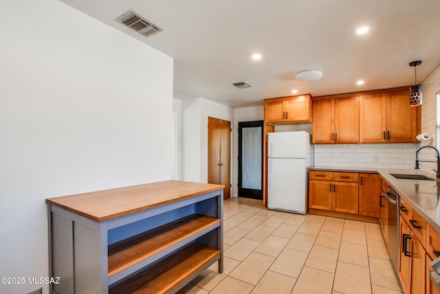 kitchen with backsplash, white refrigerator, sink, light tile patterned floors, and decorative light fixtures