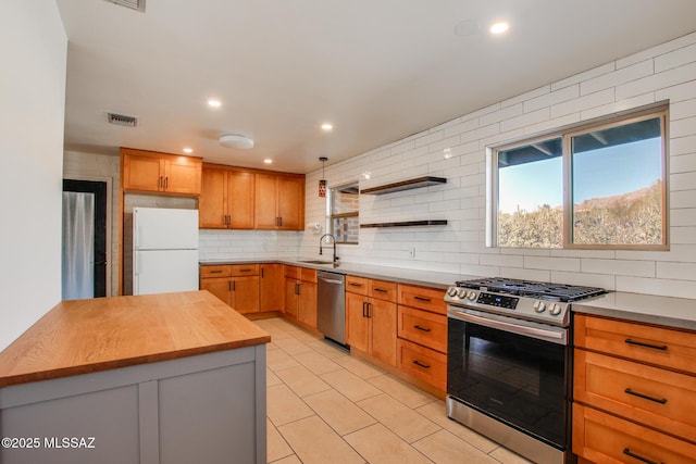 kitchen with sink, light tile patterned floors, appliances with stainless steel finishes, tasteful backsplash, and butcher block countertops