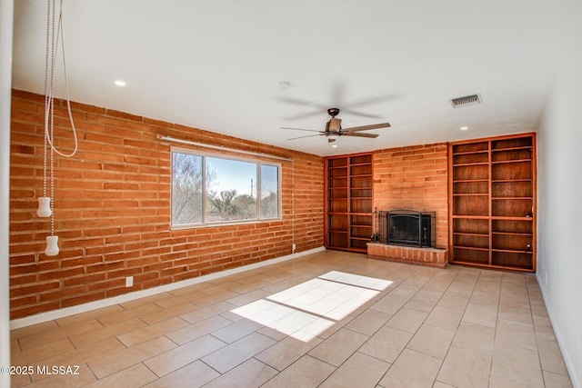 unfurnished living room featuring a brick fireplace, brick wall, ceiling fan, built in features, and light tile patterned flooring