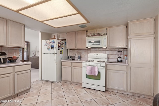 kitchen with decorative backsplash, light tile patterned floors, and white appliances