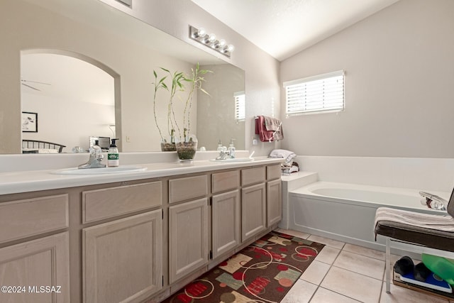 bathroom featuring tile patterned flooring, a bathtub, vanity, and vaulted ceiling