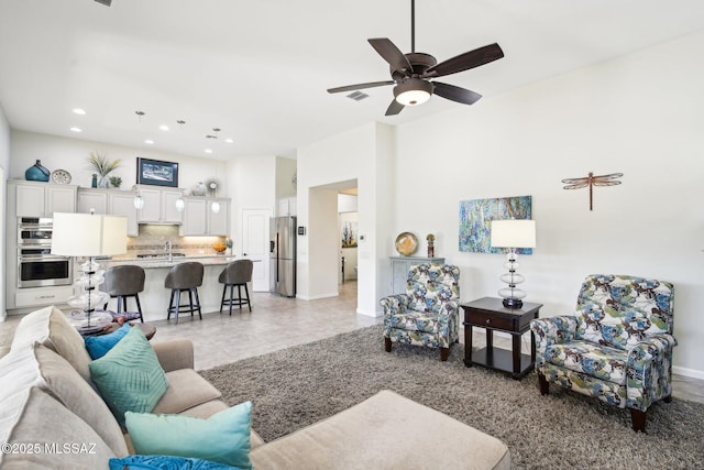 tiled living room with ceiling fan and sink