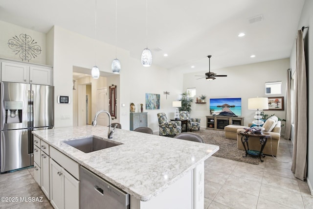 kitchen featuring ceiling fan, sink, stainless steel appliances, a center island with sink, and white cabinets