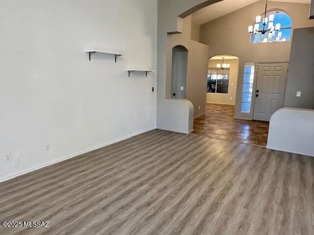 foyer entrance with wood-type flooring, high vaulted ceiling, and a chandelier