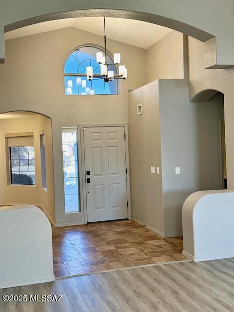 entryway featuring a notable chandelier, high vaulted ceiling, and light wood-type flooring