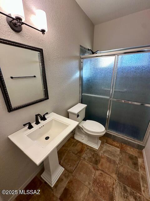 bathroom with toilet, an enclosed shower, and sink