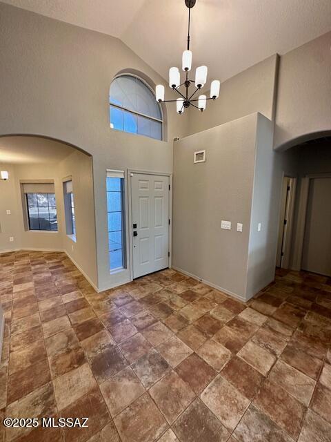 foyer with plenty of natural light, high vaulted ceiling, and an inviting chandelier