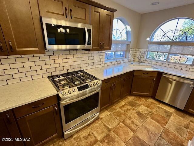 kitchen featuring backsplash, a healthy amount of sunlight, sink, and stainless steel appliances