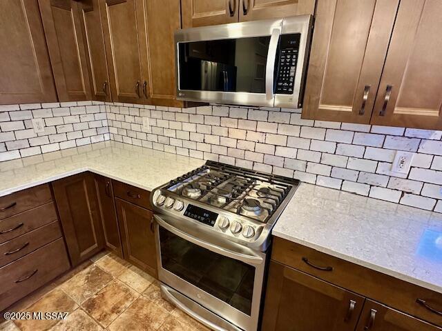 kitchen with decorative backsplash, light stone countertops, and stainless steel appliances