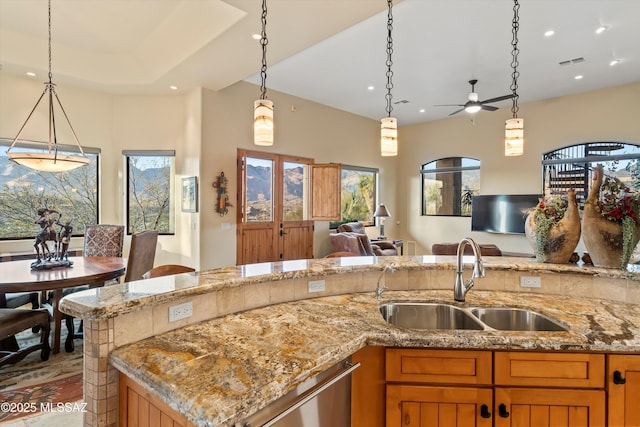 kitchen featuring light stone countertops, sink, pendant lighting, and stainless steel dishwasher