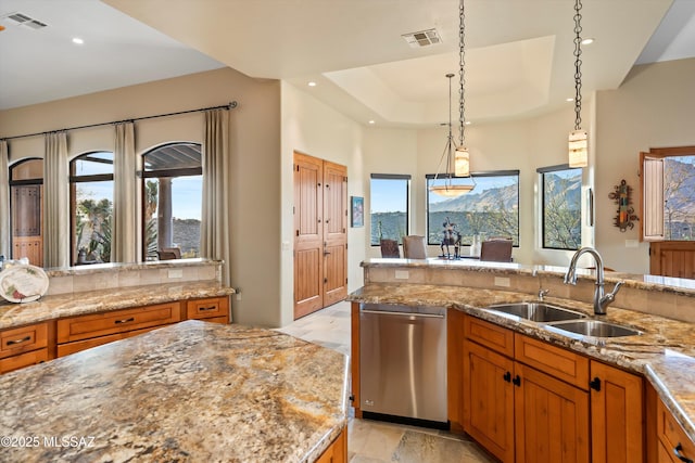 kitchen featuring stainless steel dishwasher, sink, decorative light fixtures, a raised ceiling, and light stone counters