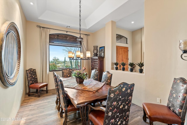 dining area featuring light hardwood / wood-style floors and a tray ceiling