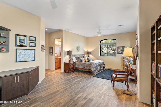 bedroom with dark wood-type flooring, ensuite bath, and ceiling fan