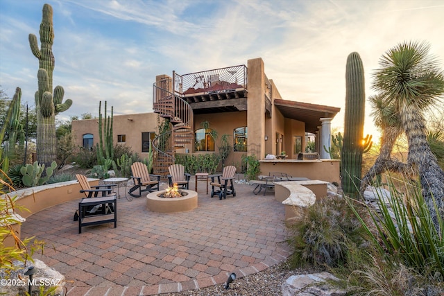 patio terrace at dusk featuring an outdoor fire pit and exterior bar