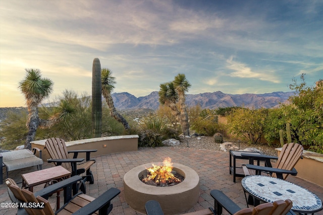 patio terrace at dusk featuring a mountain view and an outdoor fire pit