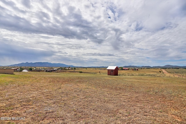 view of yard featuring a mountain view, a rural view, and a storage shed