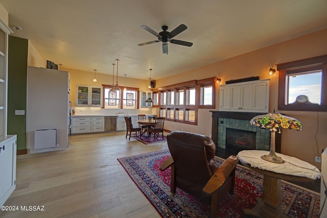 living room with ceiling fan, a fireplace, and light wood-type flooring