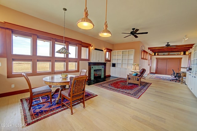 dining room featuring ceiling fan, a fireplace, and light hardwood / wood-style flooring