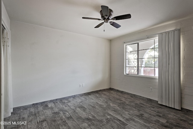 unfurnished room with ceiling fan, brick wall, and dark hardwood / wood-style floors