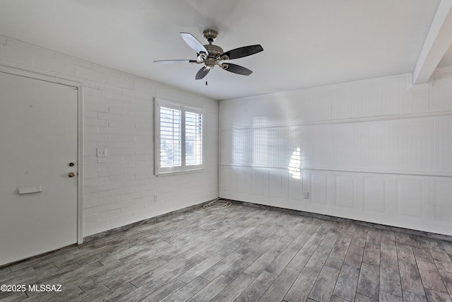 spare room with ceiling fan, brick wall, and hardwood / wood-style flooring