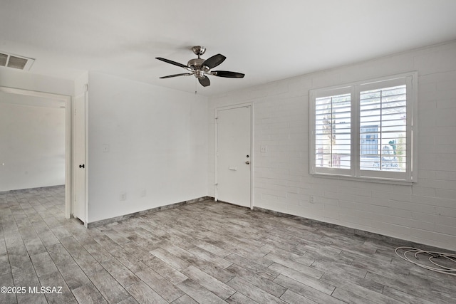 unfurnished room with light wood-type flooring, ceiling fan, and brick wall