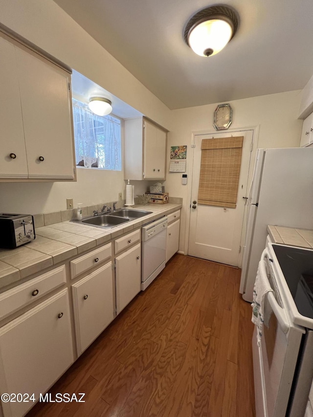 kitchen with white appliances, dark wood-type flooring, sink, tile counters, and white cabinetry