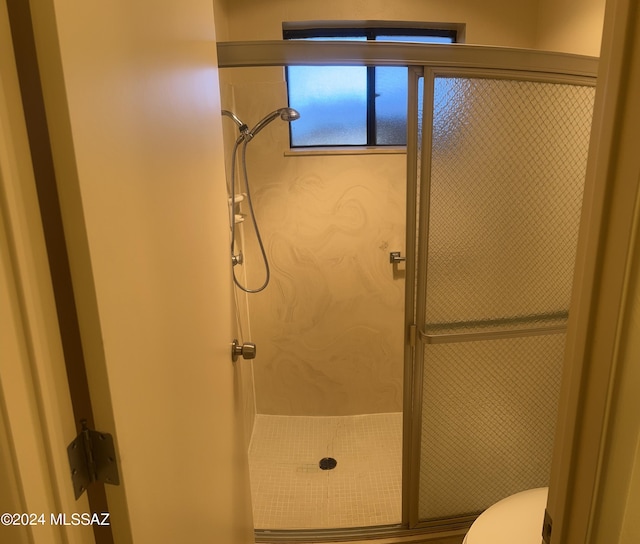 bathroom with a shower with shower door and toilet