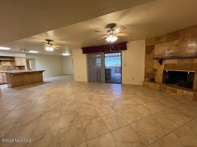 unfurnished living room featuring ceiling fan and a fireplace