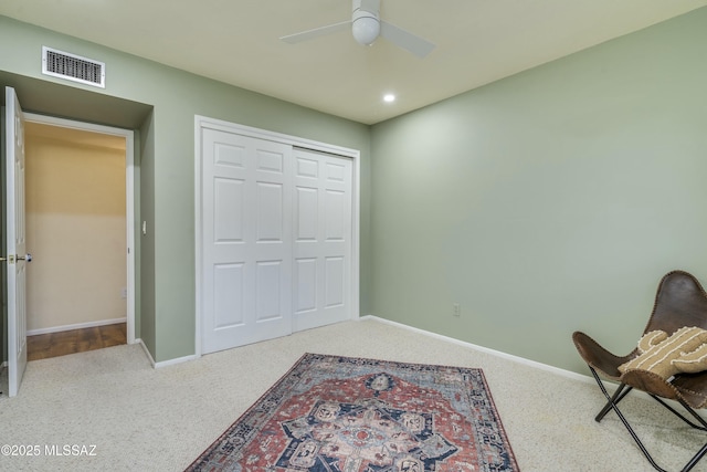 living area featuring ceiling fan and carpet