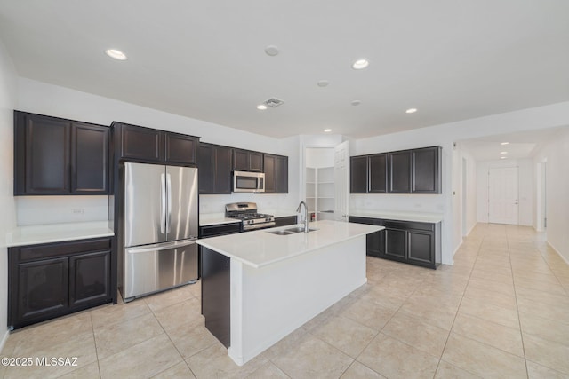 kitchen featuring light tile patterned floors, stainless steel appliances, a kitchen island with sink, and sink