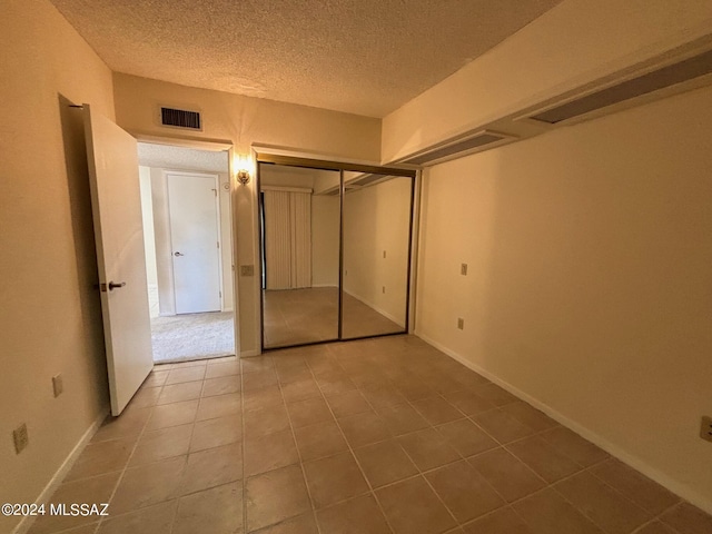 unfurnished bedroom featuring tile patterned flooring, a textured ceiling, and a closet