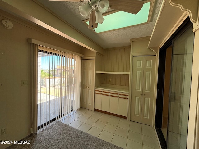 interior space with ceiling fan, light tile patterned flooring, and a textured ceiling