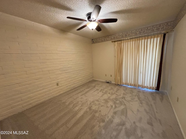 unfurnished room featuring carpet, ceiling fan, a textured ceiling, and brick wall