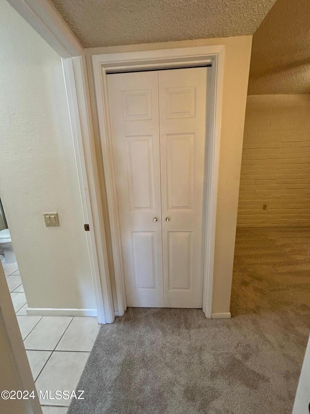 hall with a textured ceiling and light colored carpet