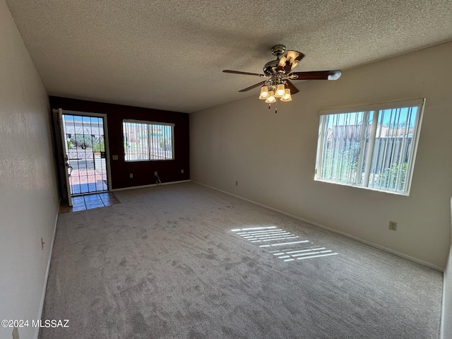 carpeted spare room featuring ceiling fan and a textured ceiling