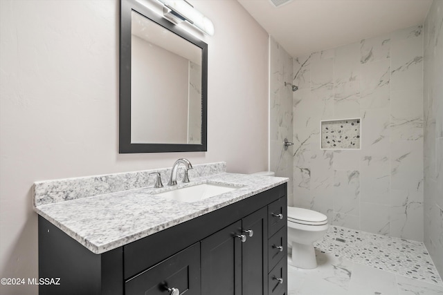 bathroom with vanity, toilet, and tiled shower