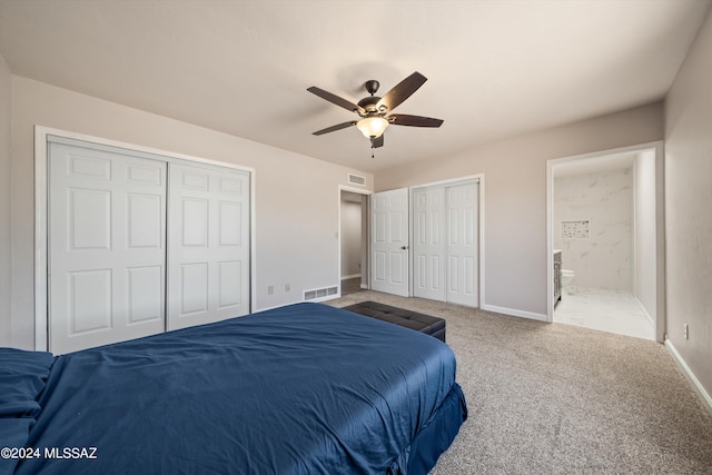 bedroom featuring connected bathroom, two closets, ceiling fan, and carpet floors