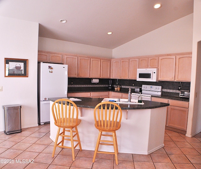 kitchen with light brown cabinets, white appliances, a center island with sink, and light tile patterned flooring