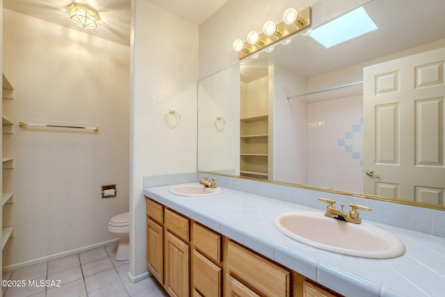 bathroom with tile patterned floors, a skylight, vanity, and toilet