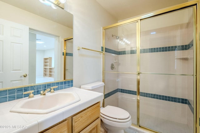 bathroom with vanity, toilet, and a shower with door